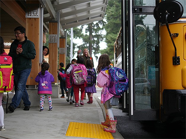 A young girl disembarks a school bus and joins her classmates at Jing Mei Elementary School on the first day of school