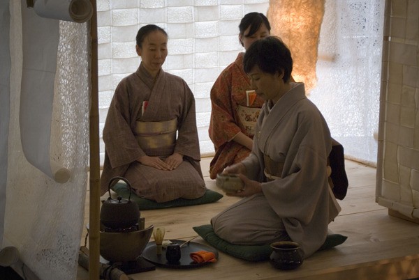 A woman prepares a cup of green tea for guests