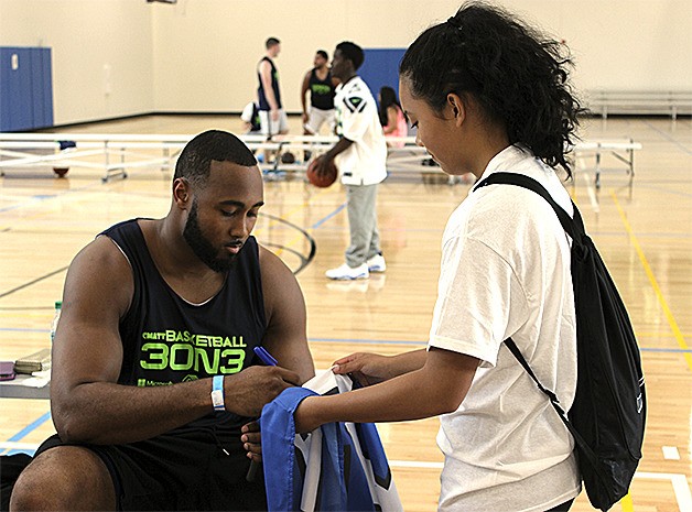 Seattle Seahawks linebacker K.J. Wright signs a shirt for a young fan during the Chris Matthews 3-on-3 basketball tournament on July 11 in Bellevue.