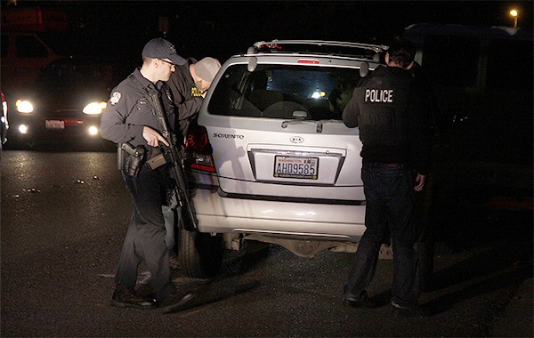 Members of the Bellevue Police Department survey the scene following the arrest of at least two people Tuesday night on SE 30th Street. The driver of the Kia Sorento and a passenger were taken into custody without incident.