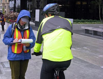 A volunteer interviews a cyclist in downtown Bellevue as part of the city's study of pedestrians and cyclists.