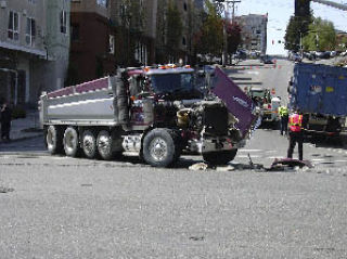 A semi-truck sits dead at the intersection of 112th Avenue and Main Street in downtown Bellevue following a collision with a garbage truck (back right). The semi-truck was proceeding through a green light when it was struck by the garbage truck traveling north on 112th