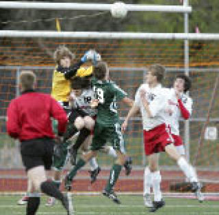 Sammamish goalie Matt Hansen blocks the ball as he collides with Skyline’s Sam Staples and Kyle Anderson.