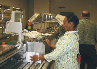 Laquita Crumwell sorts incoming ballots from the May 20 election at the King County Elections Building. Joe McCleve is behind her.