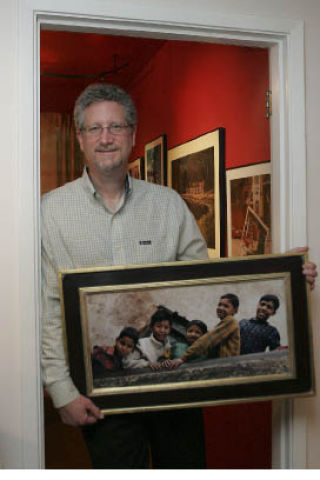 Rob Rose holds a photo he took of children in Nepal.