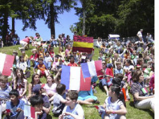 Bennett Elementary School students sit on the hillside with others from their ‘country’ as they wait for the opening of an Olympics’ ceremony Monday