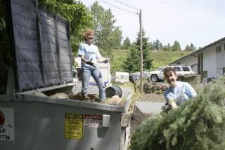 Janire Bolivar and Cindy Silverstein load debris into a dumpster as part of the cleanup at the Bellevue branch of Elder and Adult Day Services. For Silverstein