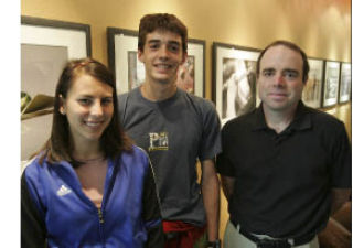 Newport High students Kaya Mills and Neil Baunsgard stand with their instructor Andrew Foti in front of the photography exhibit at the cafe in the Bellevue Arts Museum.