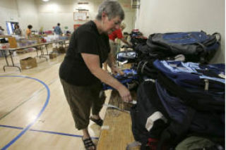Nancy Jacobs works on organizing backpacks as other volunteers help pack them with school supplies for more than 1