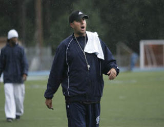 Interlake football coach Sheldon Cross barks instructions to his players during a downpour at the Saints Wednesday practice