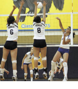 Natalie Rauschenbach and Brittney Webster of Juanita leap to block a Bellevue shot in Wednesday’s match.