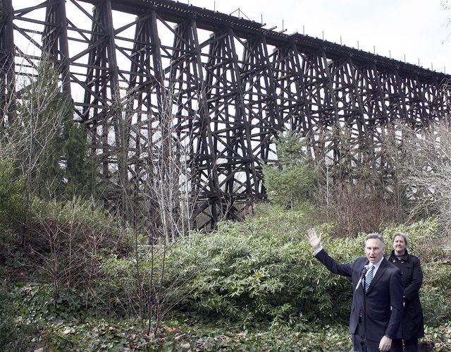 King County Executive Dow Constantine gestures to the Wilburton Trestle as he asks for public comment on the Eastside Rail Corridor trail which will traverse it.