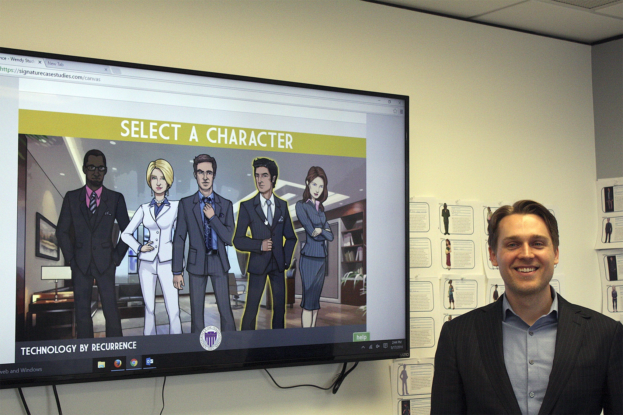 Brayden Olson stands next to the character selection screen for one of Recurrence's case models in the startup's Bellevue office.