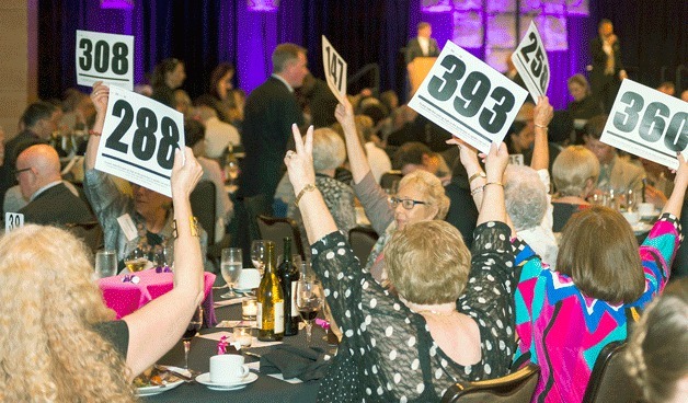 Bidders raise paddles to bid on auction items at the gala.