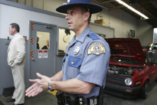 State Patrol Trooper Rick Fisher talks to a TV photographer in front of a curbstone vehicle