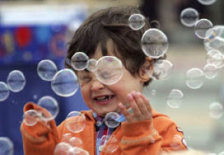 Daniel Erwin plays with bubbles during the Kindering Center graduation ceremony at Crossroads Park on Wednesday