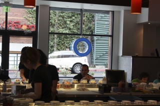 A customer at Blue C Sushi checks out the selections rolling by on a conveyor belt.