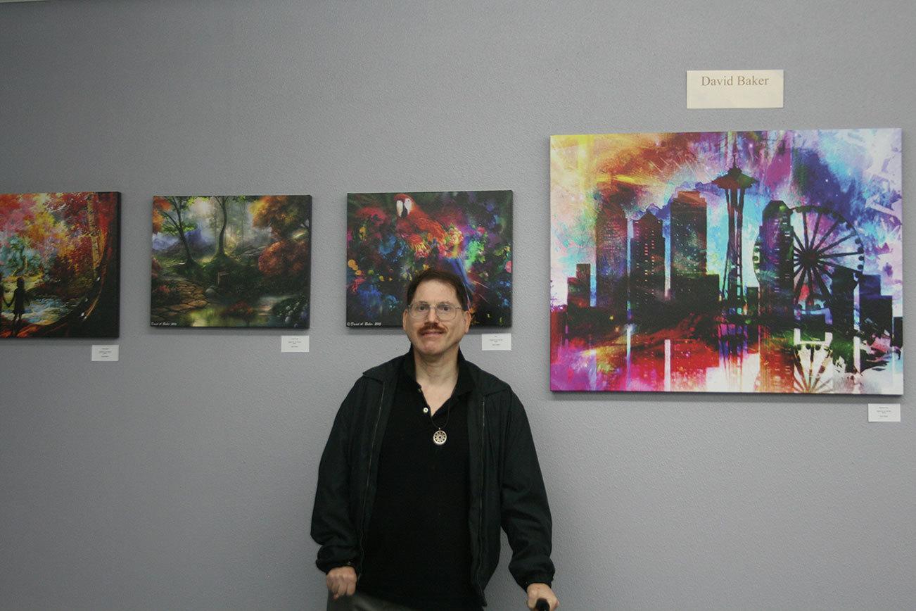 Catherine Krummey/staff photo                                Artist David Baker poses with some of his pieces on display in the Museum of Special Art’s “Colors of My World” exhibit.