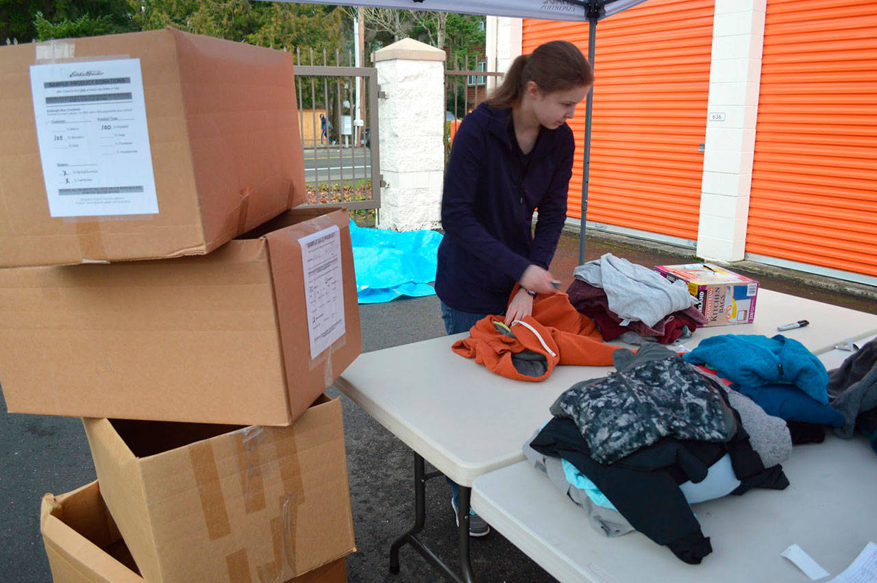 A volunteer folds clothes donated to the HopeFest event and next to her is one of the dozens of boxes to fill up the storage units rented by the HopeFest project. Alize Asplund/UW News Lab