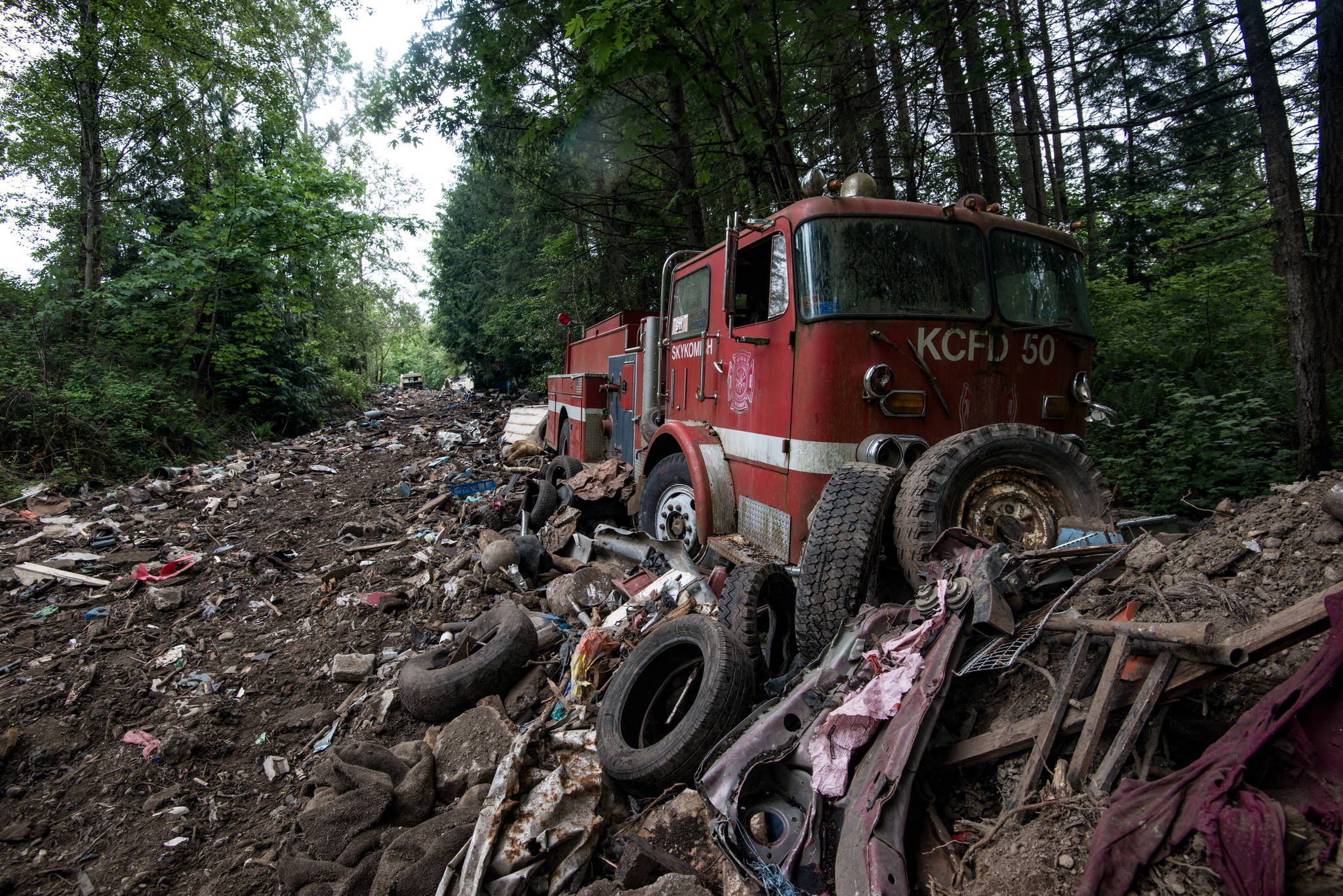 An old Skykomish Fire Engine sits amongst rubble. The pathway it sits on is riddled with tires and broken debris from other vehicles, whereas other areas are more clear of broken scrap. Photo by Caean Couto