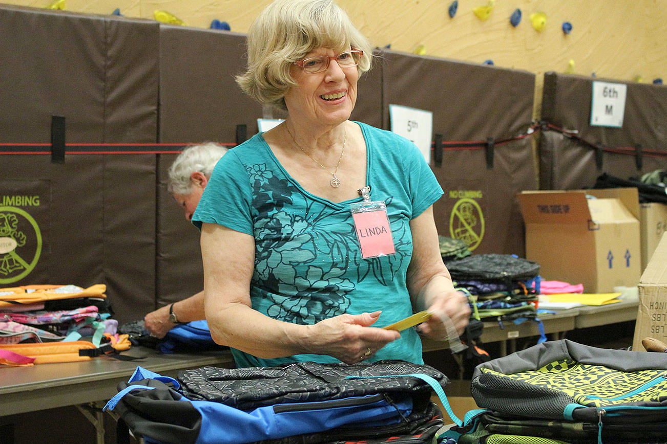 Linda Detering attaching tags to backpacks as each order is filled. Madison Miller/staff photo.