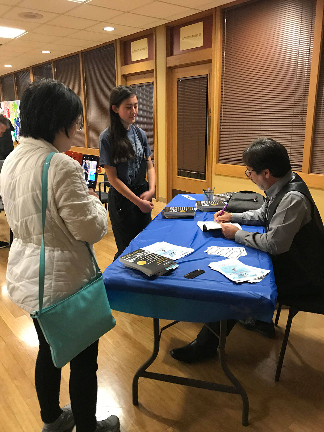 Marknisha Hervol, an eighth grader at Environmental & Adventure School in Kirkland, gets her book signed by Fredi Lajvardi during his appearance at the Peter Kirk Community Center. Samantha Pak/staff photo