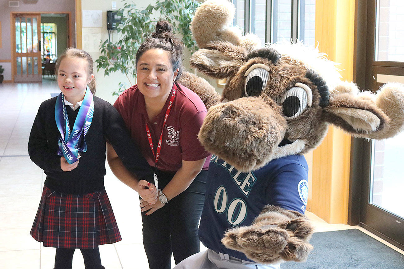 From left, Frannie Ronan, 9, and St. Madeleine Sophie Catholic School principal Martine Romero pose with Mariner Moose on Dec. 13. Stephanie Quiroz/staff photo