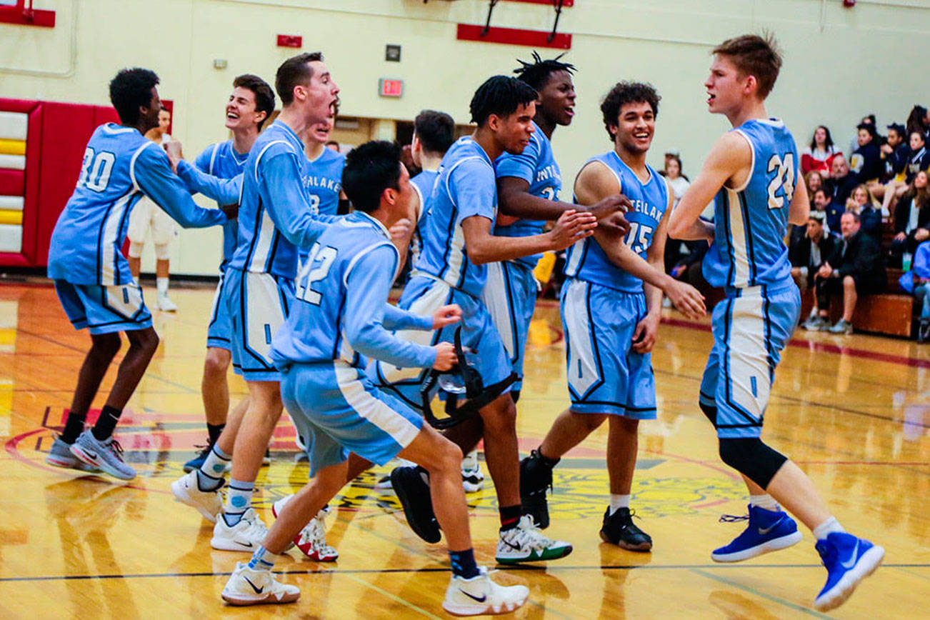 Interlake Saints players mob sophomore center Derek Kramer, right, following their dramatic 51-50 win against the Lake Washington Kangaroos in a loser-out playoff game on Feb. 6 at Newport High School in Factoria. Kramer hit two free throws with 5.7 seconds left in the game, giving his team a 51-50 lead. Photo courtesy of Don Borin/Stop Action Photography