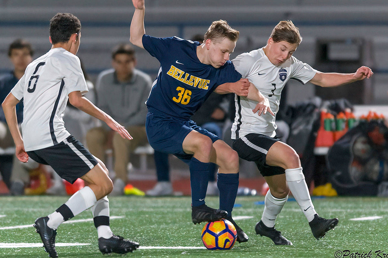 Bellevue Wolverines junior midfielder Ryan Tobin, center, battles to keep control of the ball while Lake Washington’s Dominic Koester, right, tries to take the ball away. Bellevue defeated Lake Washington 1-0 on March 21 in Bellevue. Photo courtesy of Patrick Krohn/Patrick Krohn Photography