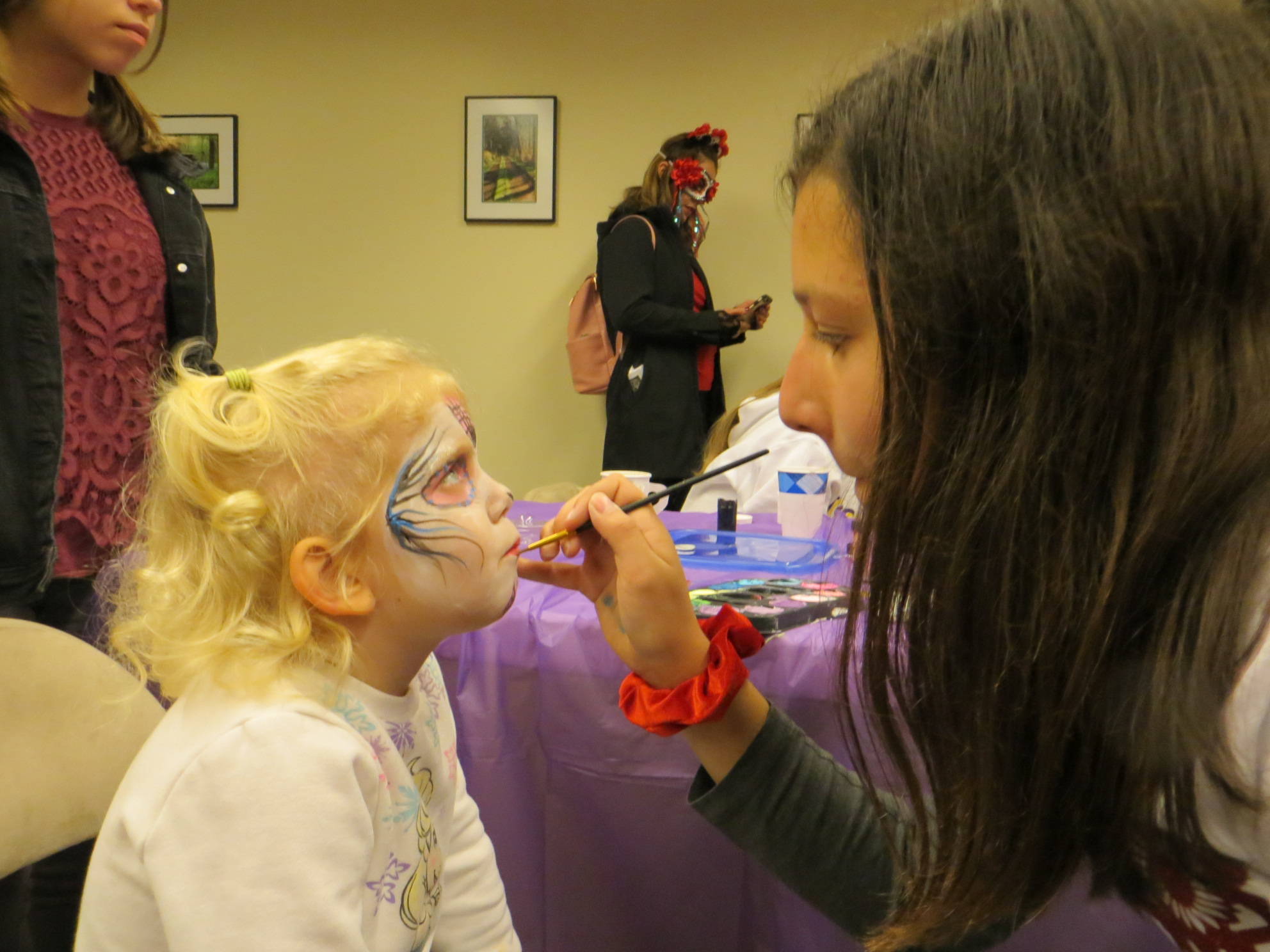 Isabelle Berube (left) gets her face painted by Saskia Visser at the Dia De Los Muertos celebration in downtown Issaquah. Samantha Pak/staff photo