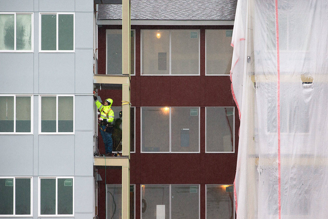 A man works on a balcony at the Cedar Pointe Apartments, a 255 apartment complex for seniors 55+, on Jan. 6, 2020, in Arlington, Washington. (Andy Bronson/The Herald)