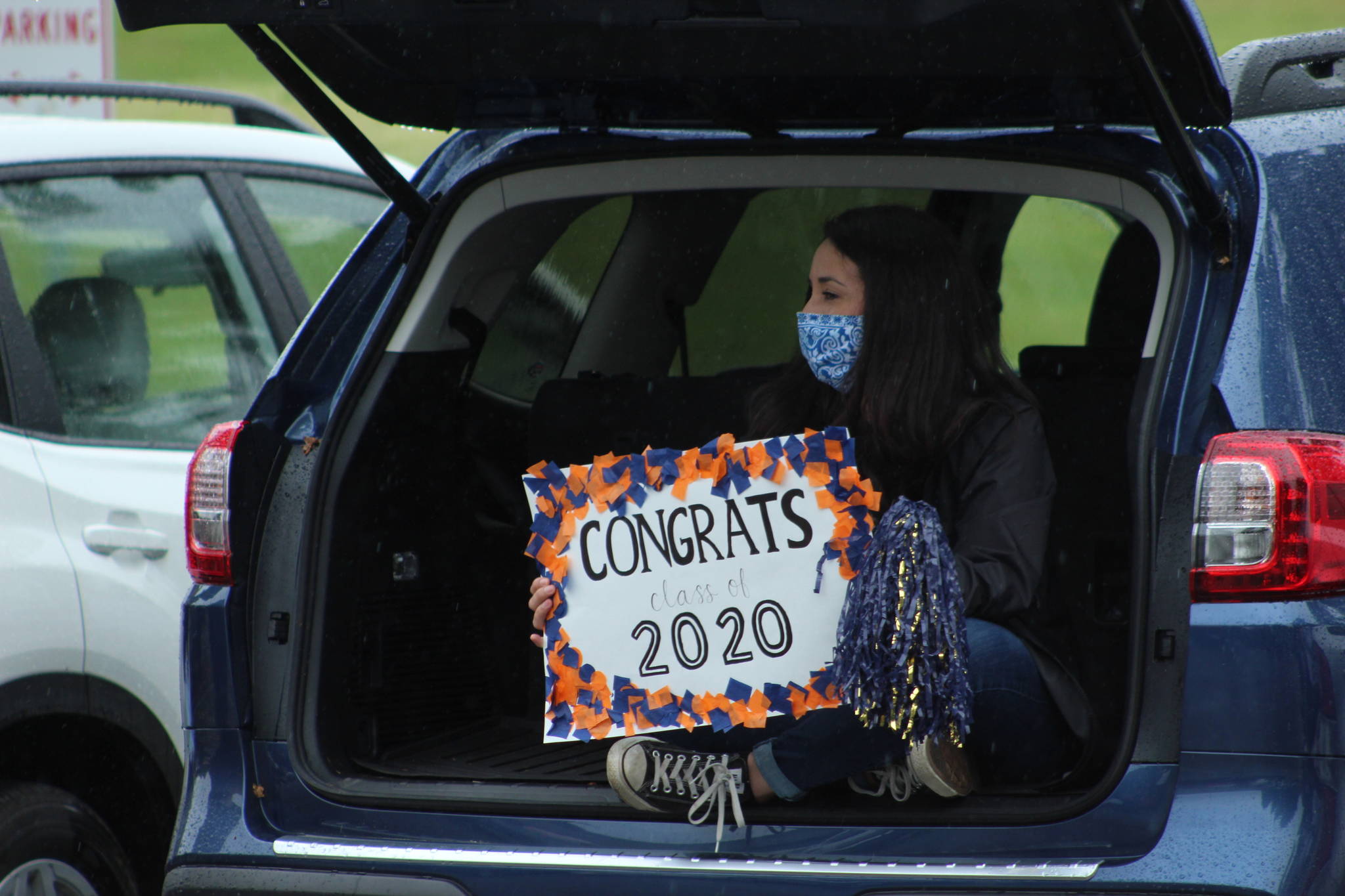 The COVID-19 outbreak closed schools statewide last spring and has led to many school districts opting for remote learning in the fall. Pictured: A Decatur High School staff member takes cover from the rain while celebrating the graduating class of 2020 in June. File photo