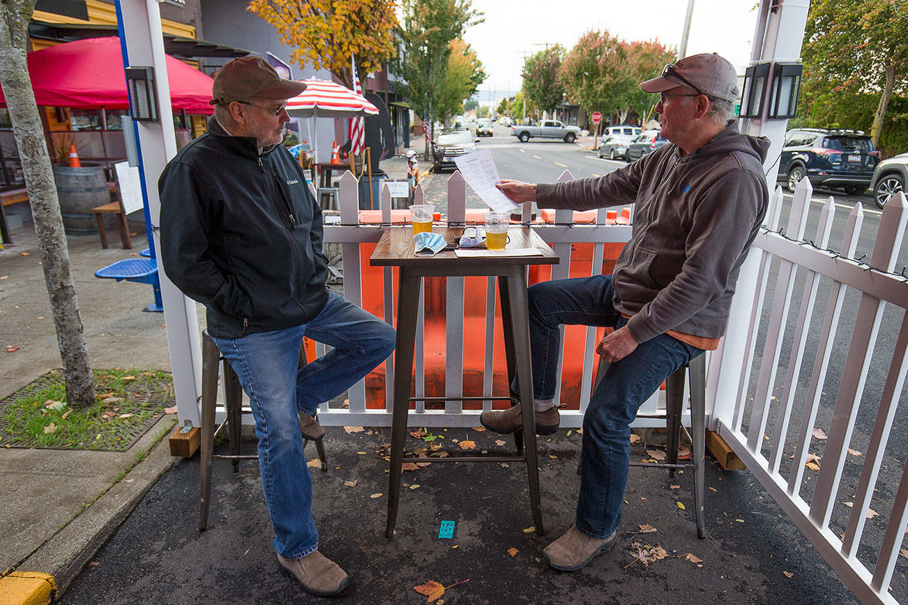 Scott McEntire and Jim Coe enjoy a drink and lunch in an outdoor seating tent at the Salish Sea Brewing Co. along Dayton Street on Monday, Oct. 12, 2020 in Edmonds, Washington. (Andy Bronson / The Herald)