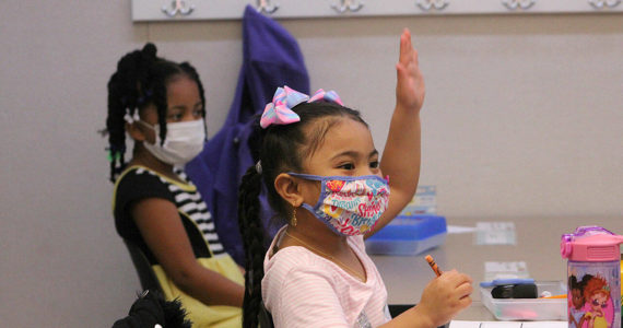 A kindergarten student at Panther Lake Elementary raises her hand during attendance on the first day of in-person learning on March 15, 2021. The DOH updated guidance that students and staff who return from isolation must wear masks in school for five days. Photo by Olivia Sullivan/Sound Publishing