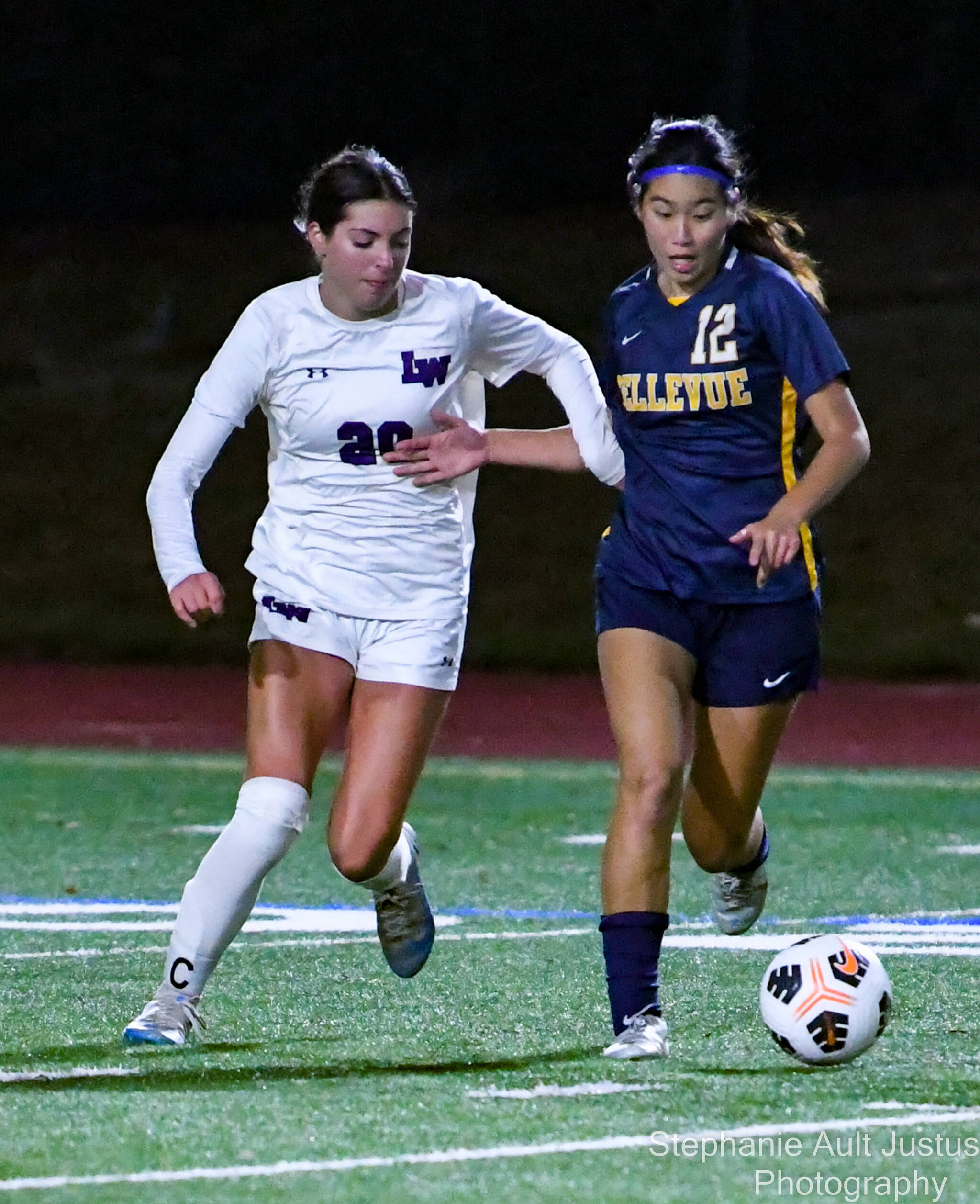 Bellevue senior Leah Uezato (#12) controls the ball while Lake Washington senior and captain, Ella Studer (#20) attempts to steal it. Courtesy of Stephanie Ault Justus.