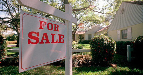 For sale sign hanging in front of house