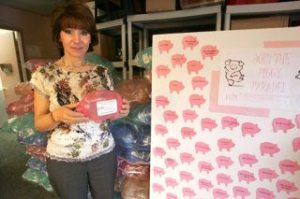 World Impact Network's Executive Director Gabriella Van Breda holds one of the piggy banks that are used to collect money to raise $50