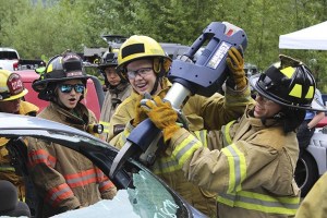 Girls use machinery to cut open a car.