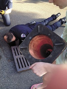 Bellevue Fire Department Lt. Paul Davison reaches in to rescue a duckling.