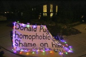 A solo female using the pseudonym Allie Turing protested in front of the home of a Bellevue man who reportedly donated $50