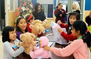 Kids at the Bellevue Boys and Girls Clubs’ site at Hidden Village apartments unwrap stuffed bears