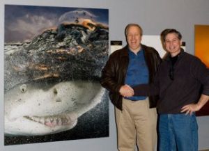 Bruce Yates (left) stands next to his photo of a smiling shark as Steve Freligh