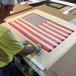 Mark Schneider with Phoenix Art Restoration works on the flag hand-sewn by the Bellevue Minute Women (Photo courtesy of Bob Shay).