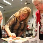 One of Deanna Carr&rsquo;s sisters, center, and her mother, right, sprinkle seeds onto the florograph of Carr&rsquo;s face that will ride atop Donate Life&rsquo;s float in the 2017 Rose Parade (Allison DeAngelis/staff photo).