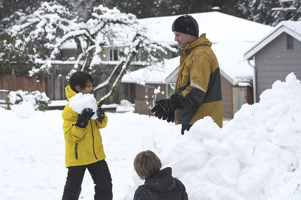 Two boys help their dad build a snow fort in Bellevue (Allison DeAngelis/staff photo).
