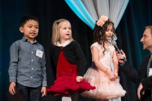 Charles Vejano, Macy Gray, and Zumorod Mohammed tell their Principal, Chas Miller, and nearly 1,000 Spring for Schools luncheon guests about learning to read at Ardmore Elementary School. Proceeds from the Benefit Luncheon go to Bellevue Schools Foundation, which supports quality public education in Bellevue. Photo courtesy Mike Nakamura Photography.