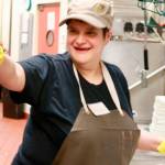 Maslan joyfully greets a co-worker as she washes dishes at work at an Issaquah restaurant where she has worked for over six years. Photo courtesy of Regina Friedland