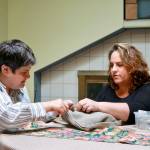 Listening intently to her sister Michelle&rsquo;s patient instructions, they work together to fix the broken zipper pull on her purse. Maslan is focused on their task in the family&rsquo;s Bellevue home. Photo courtesy of Regina Friedland