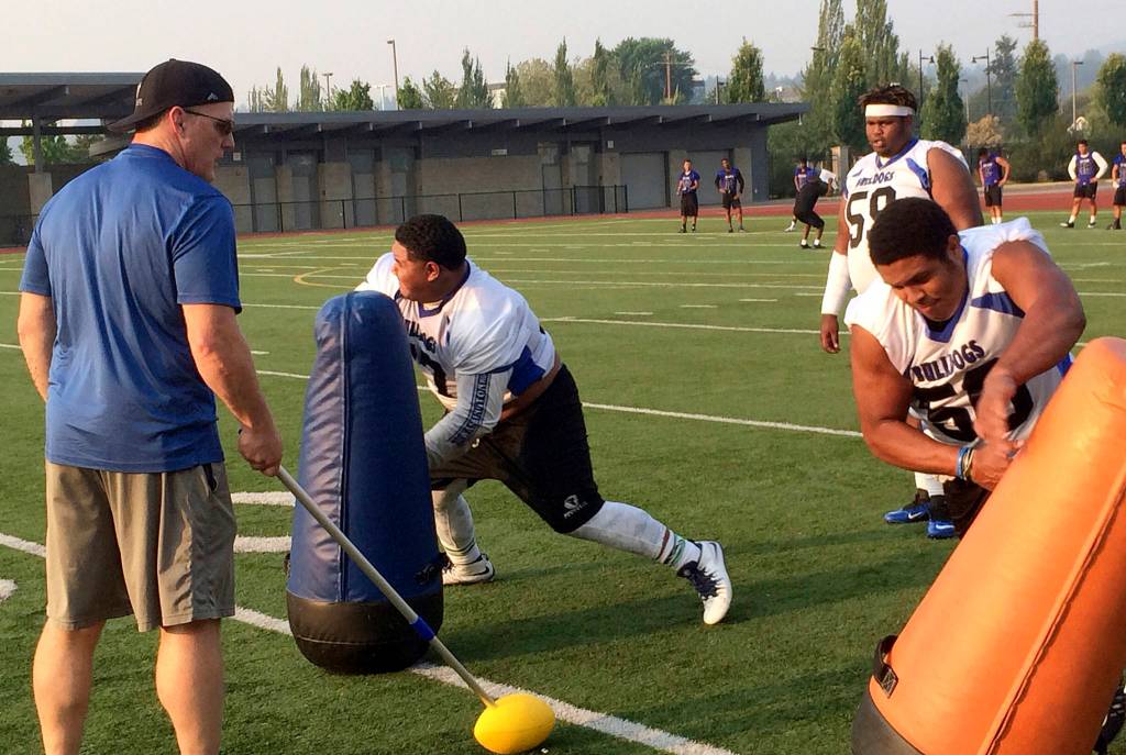 Shaun Scott/staff photo                                Eastside Bulldogs defensive lineman, James Taupule right, explodes out of his stance while Bulldogs&rsquo; head coach Kevin Bouwman, left, shouts words of encouragement.