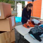 A volunteer folds clothes donated to the HopeFest event and next to her is one of the dozens of boxes to fill up the storage units rented by the HopeFest project. Alize Asplund/UW News Lab
